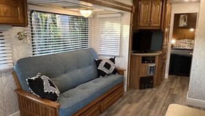 Un intérieur de camping-car accueillant, avec un canapé, des meubles en bois et un coin cuisine.