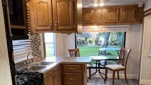 Une cuisine dotée de meubles en bois, d’une cuisinière à gaz, d’un évier et d’un coin repas avec une table et des chaises.