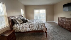 Une chambre à coucher avec un lit, une commode et un téléviseur fixé au mur.
