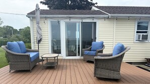 En overdækket terrasse med fletmøbler og en skydedør.