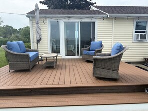 A covered deck with wicker furniture and a sliding glass door.