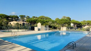 Ein rechteckiger Pool mit Metallleitern an beiden Seiten, umgeben von einer gefliesten Terrasse.