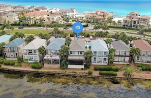 Uma área residencial costeira com casas modernas, uma marina e uma praia ao fundo.