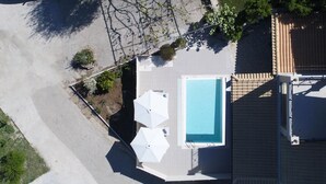 Vista aérea de um bairro residencial com piscina, varanda coberta e jardim.
