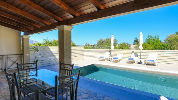 Uma área de piscina ao ar livre coberta, com espreguiçadeiras e uma mesa de vidro.