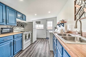 A kitchen with blue cabinets, a stainless steel sink, and a stove.