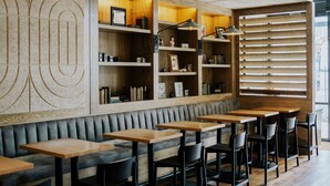 A modern restaurant interior with wooden shelves, a cushioned bench, and wooden tables. - Holman Riverfront Park Hotel Salem, Tapestry by Hilton (Salem)