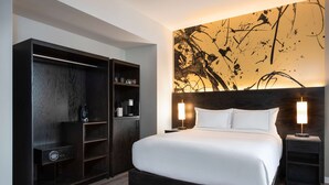 A modern hotel room with a large bed, a dark wooden wardrobe, and a wall art piece. - Holman Riverfront Park Hotel Salem, Tapestry by Hilton (Salem)