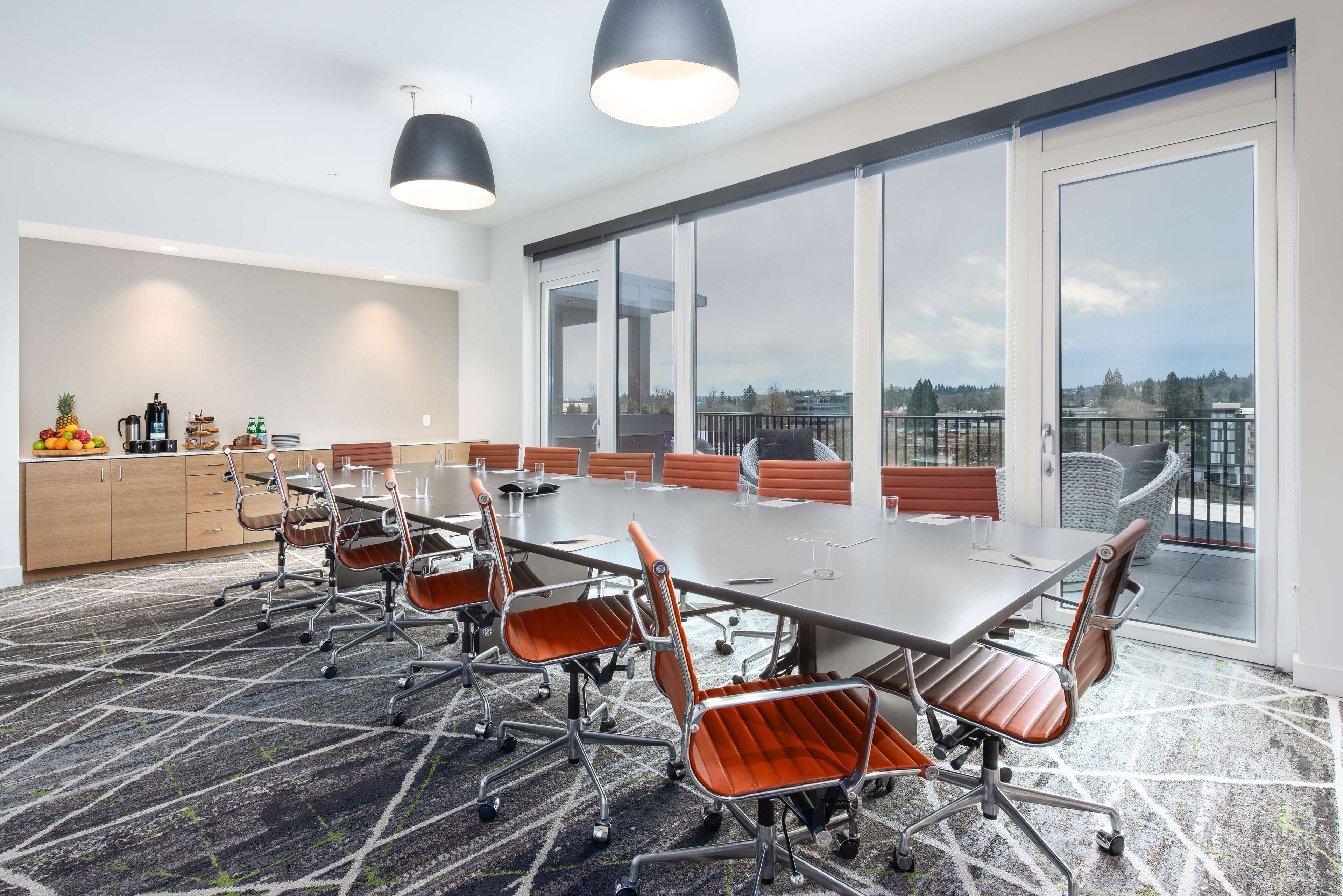A conference room with a large table, chairs, and a view of the city through large windows.