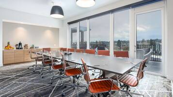 A conference room with a large table, chairs, and a view of the city through large windows.