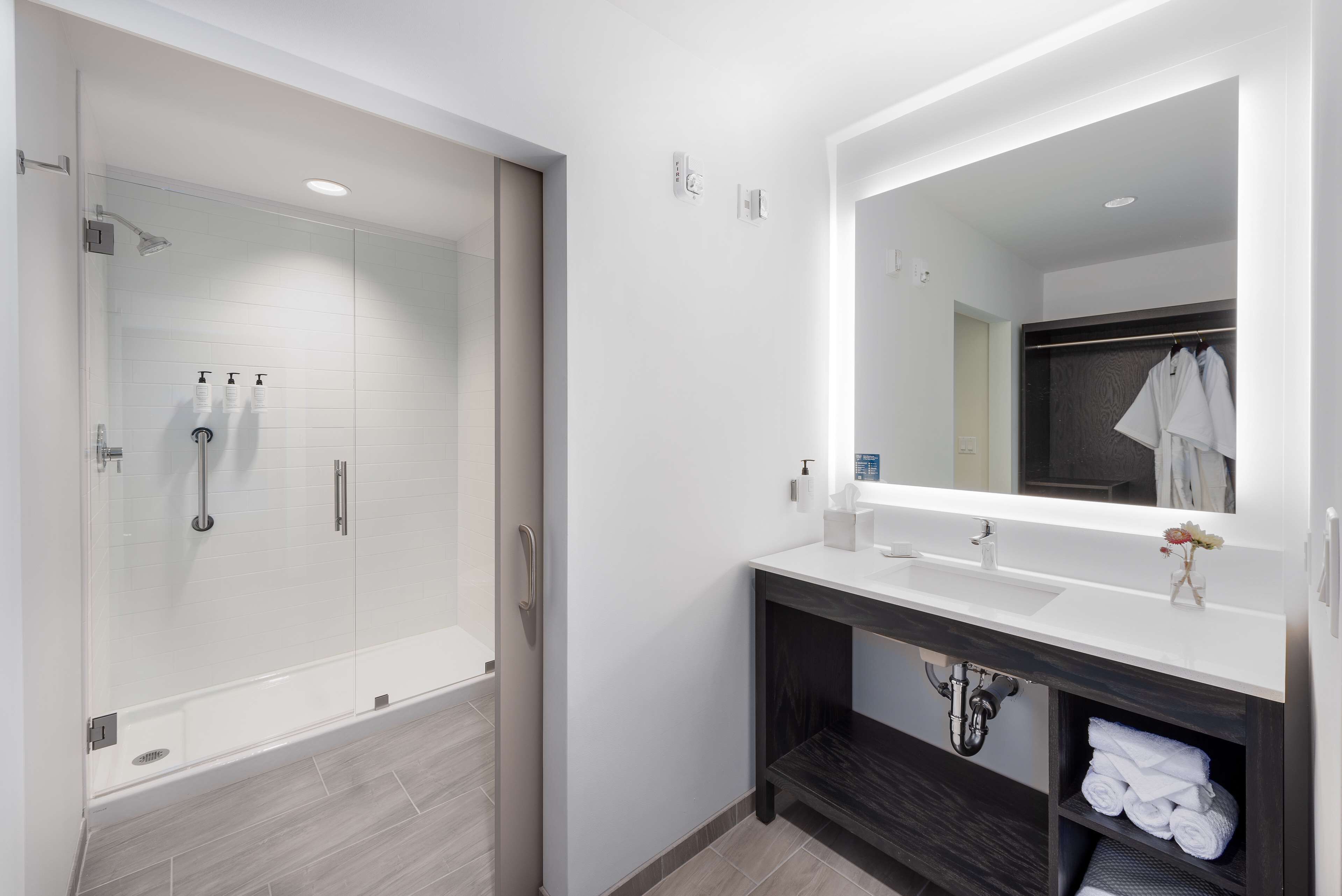 A modern bathroom with a glass-enclosed shower, a white sink with a dark vanity, and a mirror above the vanity.