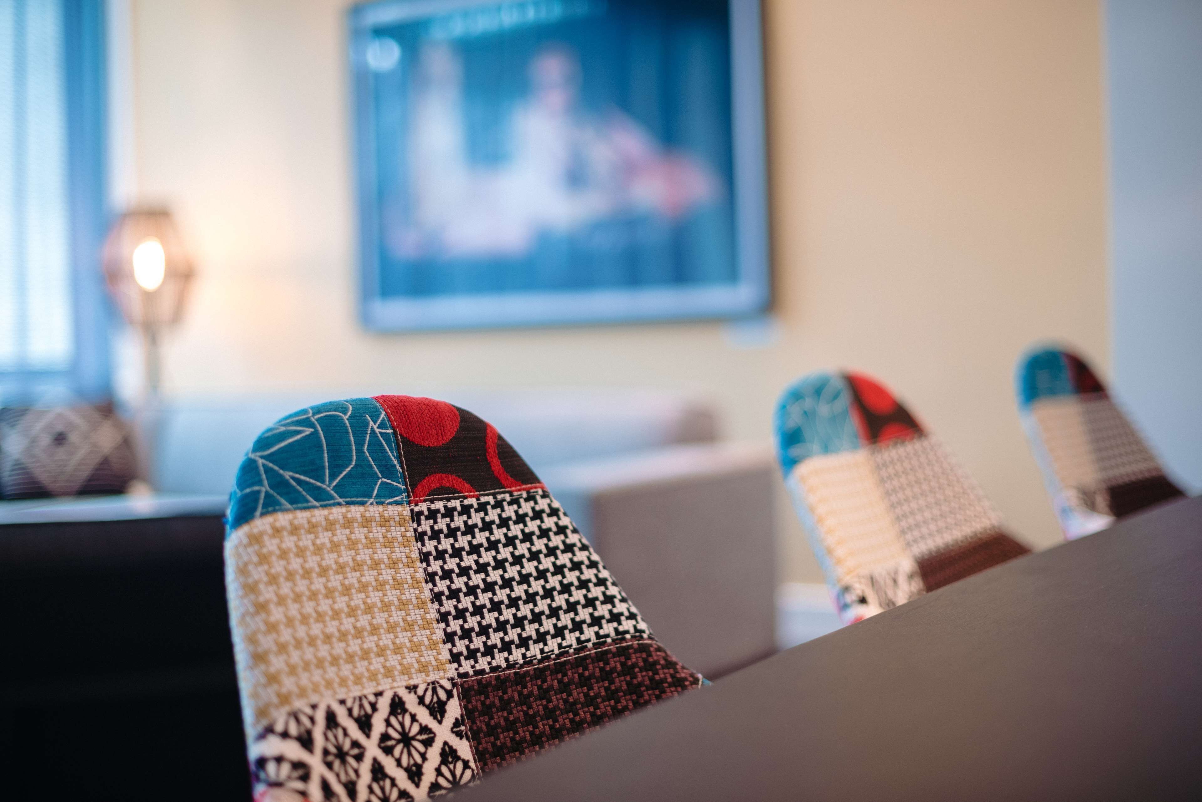 En närbild på ett mönstrat tyg, troligen från en kudde eller ett möbeltyg, med en blandning av geometriska och blommiga motiv.