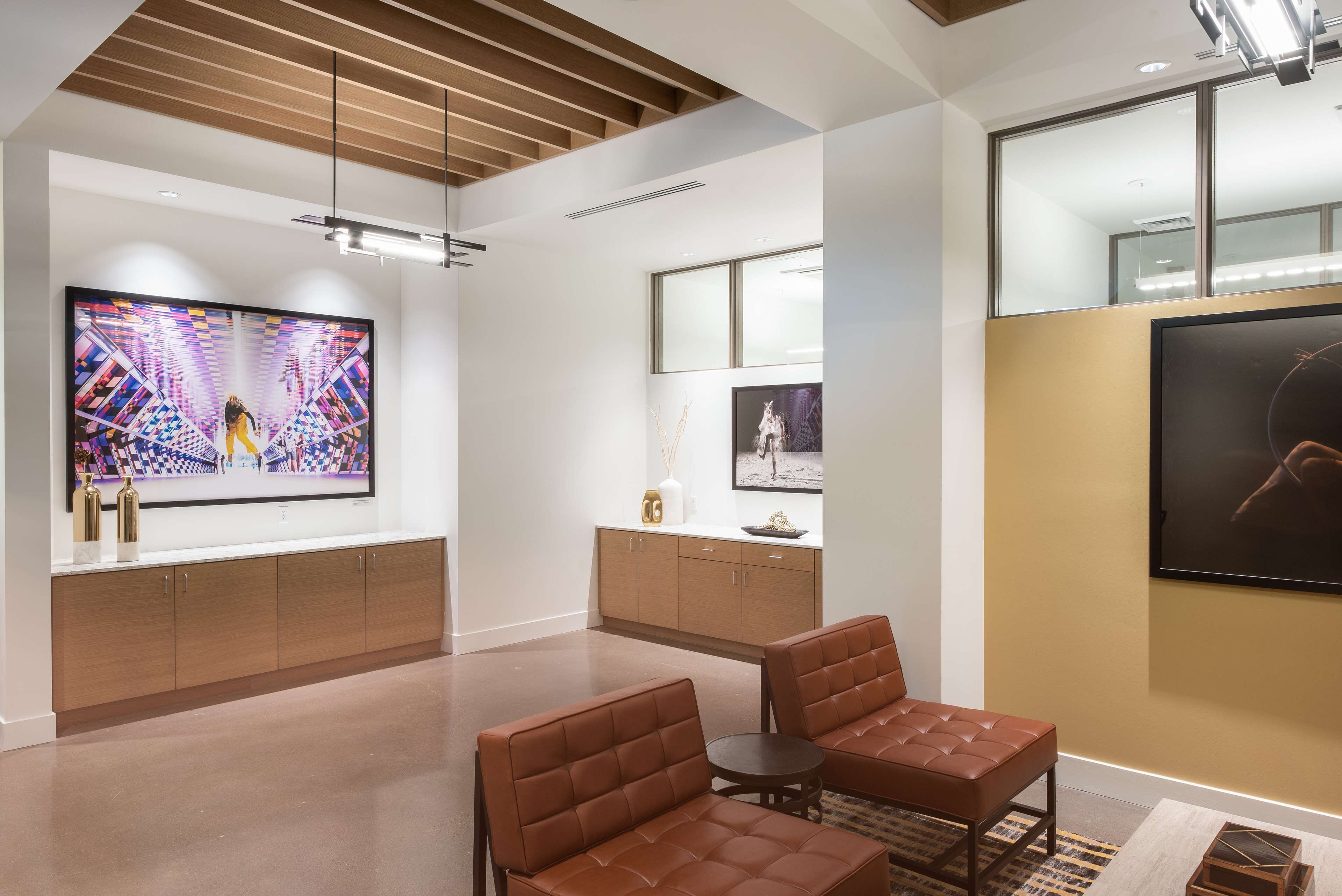 A modern interior with a wooden ceiling, a large flat-screen TV, a wooden cabinet, and two leather sofas.