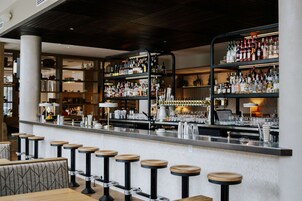 A bar area with multiple stools and shelves stocked with bottles.