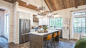A spacious kitchen with a large island, stainless steel appliances, and wooden accents. - Collins Creek 1 BR- Woodland Hills- 2 acres creek (Broken Bow)