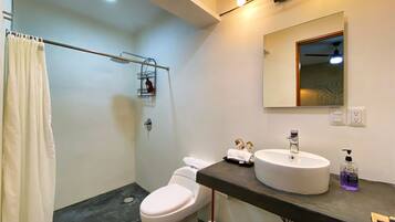 Un baño moderno con inodoro, lavamanos, espejo y ducha.