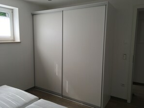 Une pièce dotée d’un placard avec porte coulissante, d’une fenêtre et d’un lit.
