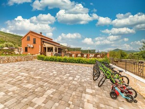 Un bâtiment doté d’une cour pavée, d’une rangée de vélos et d’un mur en pierre.