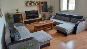 Un salon moderne avec un canapé, un téléviseur et une table basse.