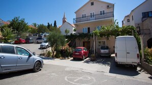 Une rue résidentielle bordée de voitures garées, avec une église et un immeuble à deux étages doté d’un balcon.