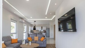 A modern living room with a grey sofa, a coffee table, and a TV mounted on the wall. - Luxury Villa La nonna Ana - entertainment,fitness,pool,sea view (Kastel Sucurac)