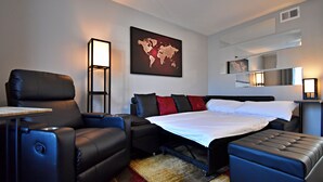 A modern hotel room with a large bed, a sofa, a small table, and a desk. - ✪ King Beds ✔ 2 Bdr Townhouse w/ Private Backyard (Bryan)