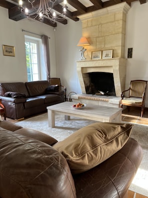 A living room with a stone fireplace, leather sofas, and a wooden coffee table. - Cosy house between Bordeaux and Saint-Emilion (beychac et cailleau)