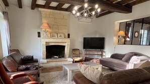 Una sala de estar con chimenea, sofás de cuero, una mesa de centro y un televisor.