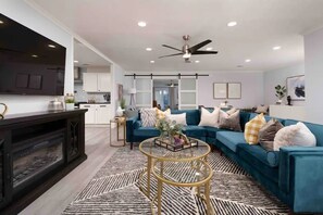 A modern living room with a blue sofa, a fireplace, and a ceiling fan.