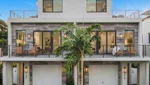 A modern two-story building with a balcony, large windows, and a palm tree in the foreground. - Luxury Paradise, walk to Las Olas -5 mins to Beach (Fort Lauderdale)