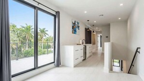 A modern interior with large windows, a kitchen area, and a staircase. - Luxury Paradise, walk to Las Olas -5 mins to Beach (Fort Lauderdale)