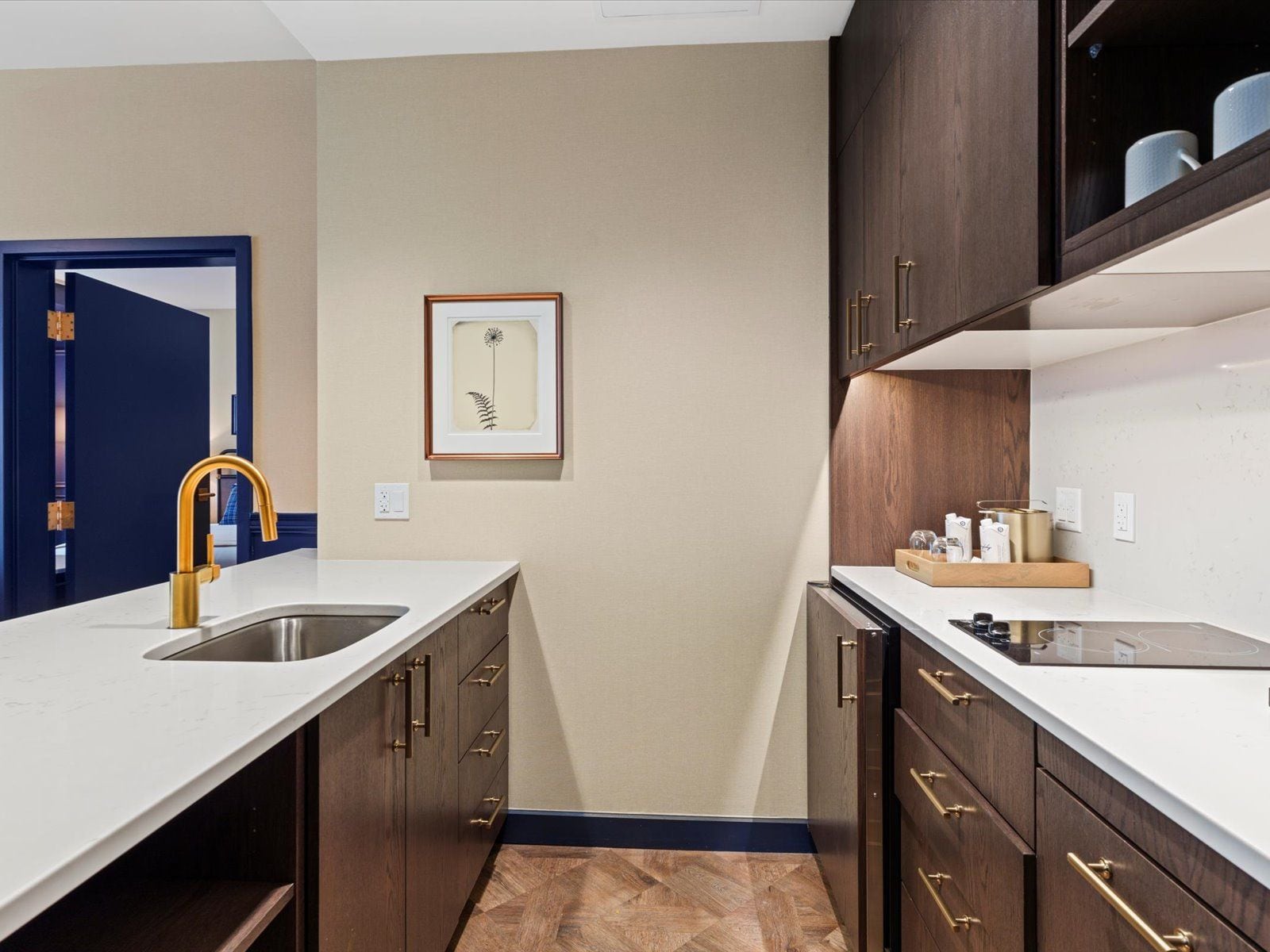 A modern kitchen with a double sink, wooden cabinets, and a framed artwork on the wall.