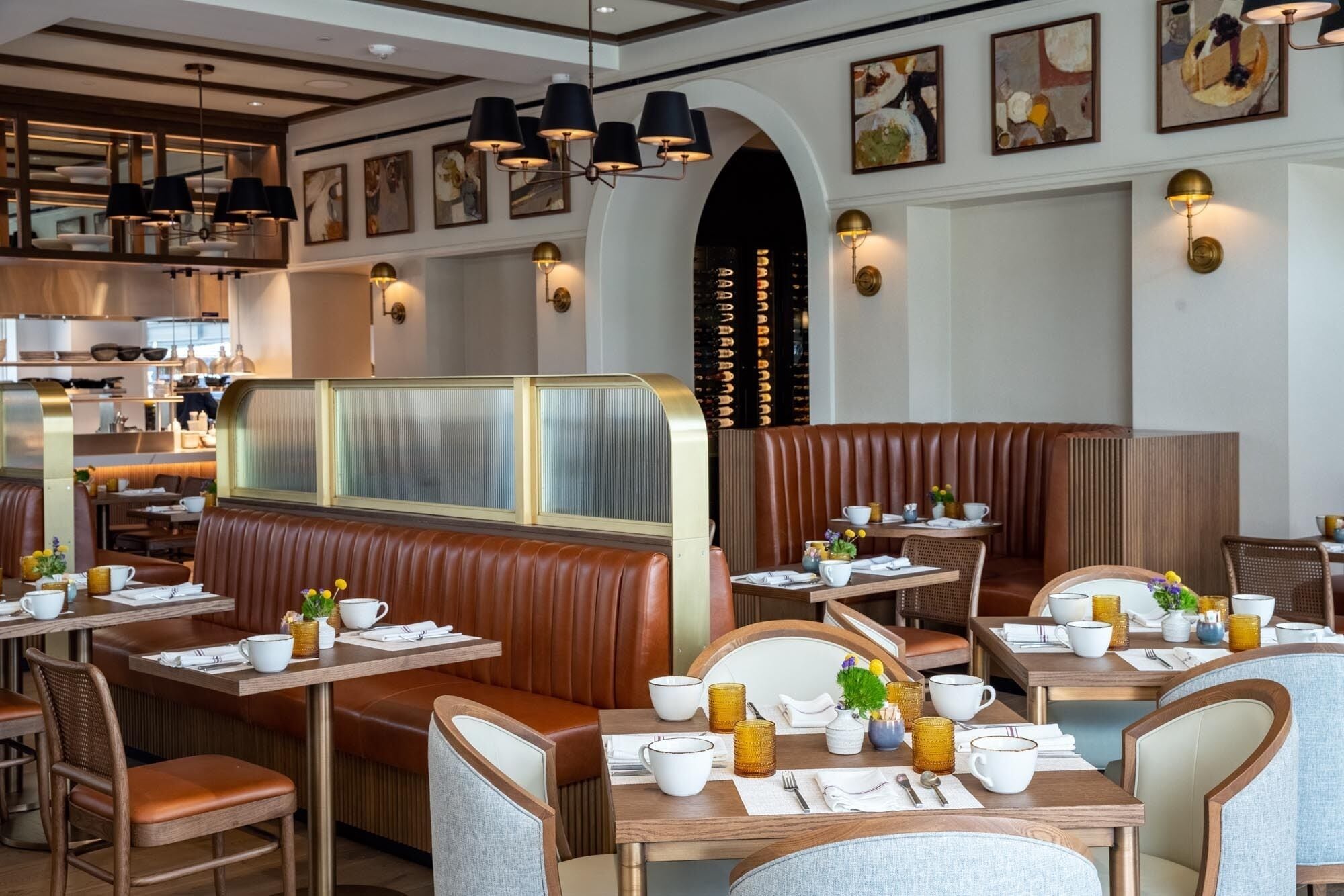 Interior de restaurante com cabines e mesas, algumas com plantas e xícaras.