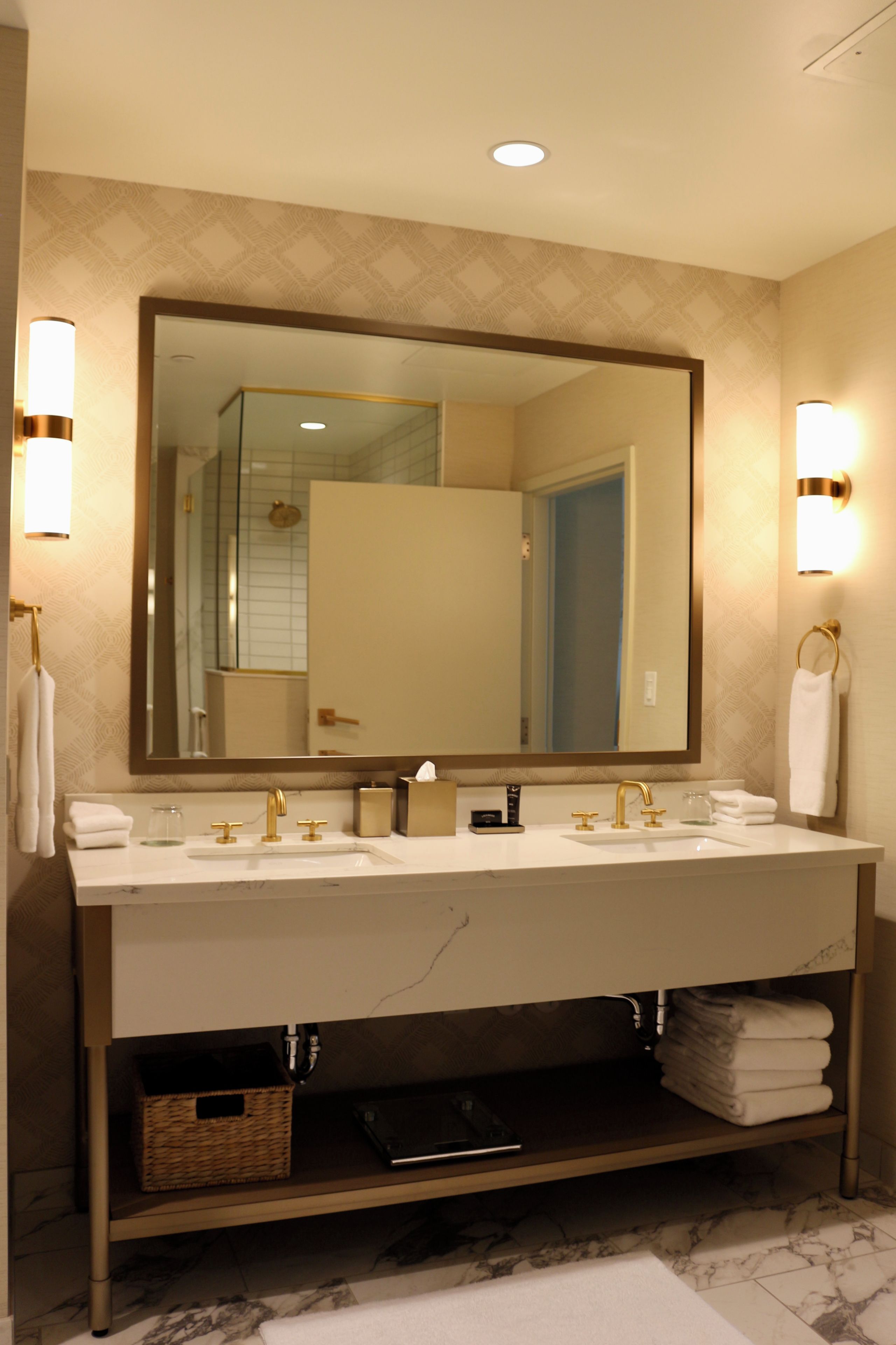 A bathroom with a large mirror, two sinks, and towel racks.