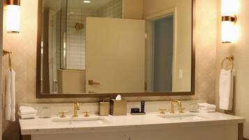 A bathroom with a large mirror, two sinks, and towel racks.