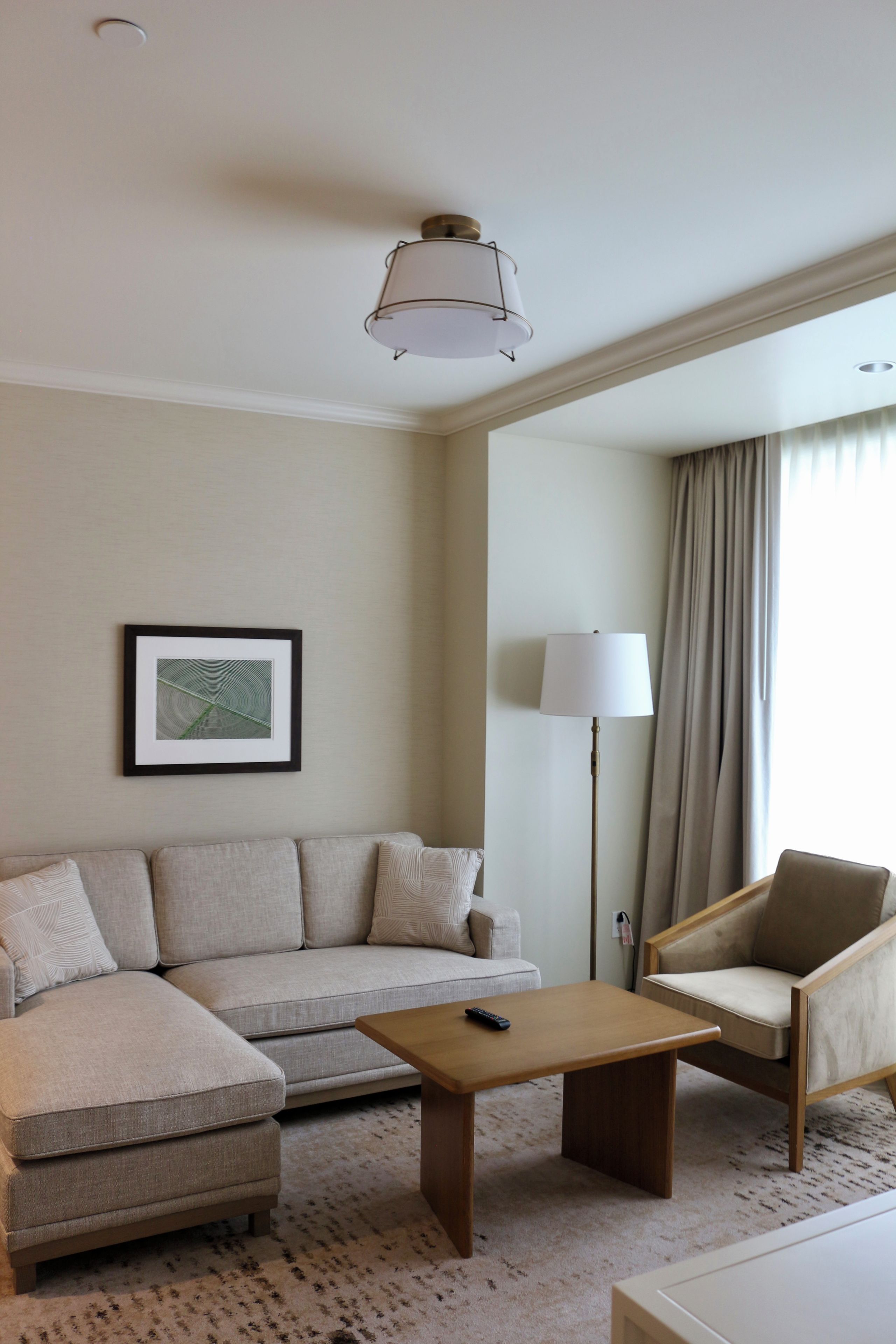 A hotel room with a sofa, a small table, a chair, a lamp, and a framed picture on the wall.