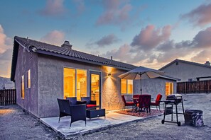Una casa moderna con patio amoblado, mobiliario exterior y una parrilla.