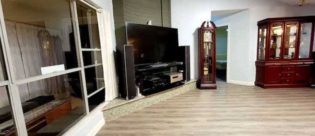 Un salon équipé d’un téléviseur à écran plat, d’un meuble en bois et d’une grande horloge.