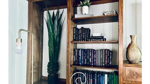 A wooden bookshelf with books, a potted plant, and a decorative vase.