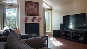 Una sala de estar con chimenea, un televisor de pantalla plana grande y un sofá.