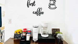 Un mur décoré sur le thème du café, avec notamment un autocollant mural sur lequel on peut lire « mais d’abord, un café » et une machine à café.