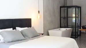 A modern hotel room with a large bed, a glass-enclosed shower, and a bedside table. - 2 Floor PH in Provenza, Poblado - 4BR / 4Bath (Medellín)