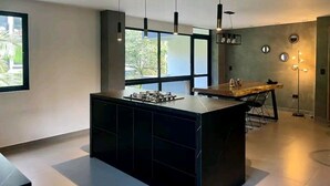 A modern kitchen with a central island, pendant lighting, and a view of the outdoors. - 2 Floor PH in Provenza, Poblado - 4BR / 4Bath (Medellín)