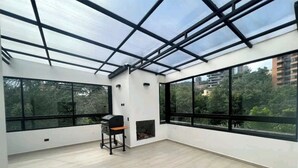A spacious room with large windows, a fireplace, and a ceiling with a glass structure. - 2 Floor PH in Provenza, Poblado - 4BR / 4Bath (Medellín)