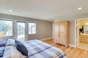 A bedroom with a bed, a wooden wardrobe, and a door leading to a bathroom. - Stunning Lakeside House w/ Deck + Water Views (Lakeside)