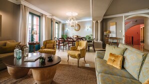 A spacious living room with a round coffee table, two armchairs, a sofa, and a dining area with a chandelier. - Palace in the center of the town with pool (Sevilla)