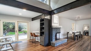 Una sala de estar moderna con chimenea, piso de madera y un comedor con una mesa y sillas blancas.
