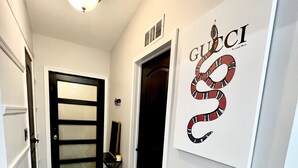 A hallway with a black and white striped rug, a black door, and a wall-mounted artwork of a snake.