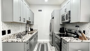 A modern kitchen with grey cabinets, a central island, and a black and white rug.
