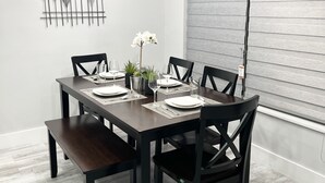 A dining area with a dark wooden table, black chairs, and a modern chandelier.
